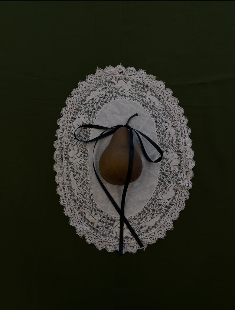 Pear with a black stem on a decorative white plate against a dark background